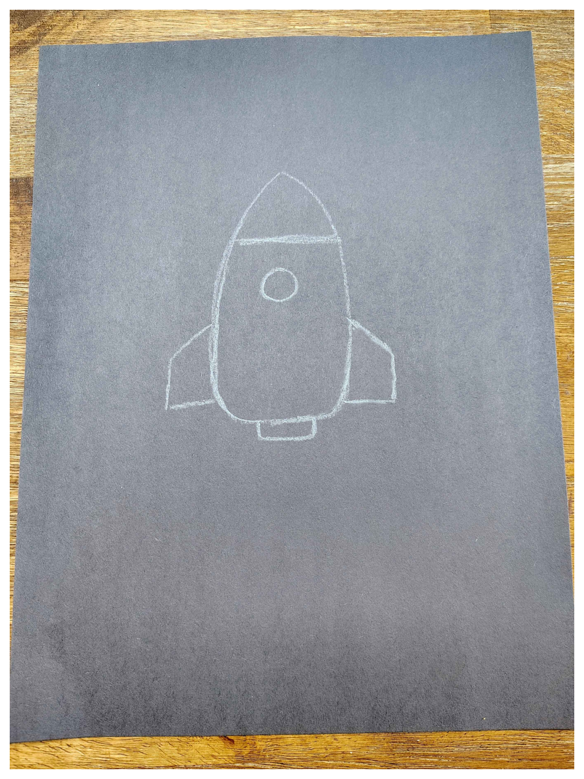 Rocket Craft- Step 1- White rocket ship on black paper -Kids Activities Blog